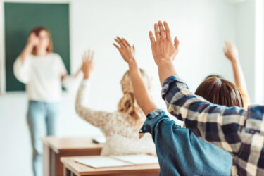 Students raising their hand  during a lecture in a classroom