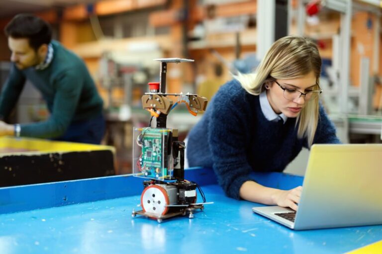 Young beautiful female engineer testing and programming robot